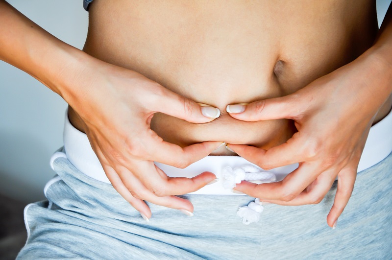 Woman pinching excess belly fat