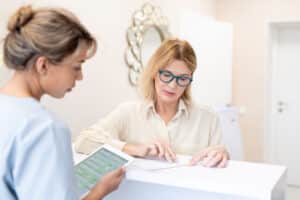 Woman meeting with receptionist to discuss insurance options for breast reconstruction after mastectomy