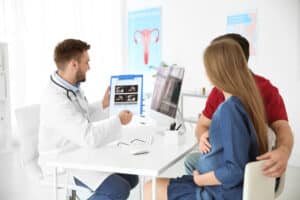 Doctor showing ultrasound images to a pregnant woman and her partner during a prenatal consultation
