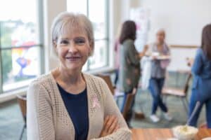 Older woman wearing a pink breast cancer ribbon who may be considering breast reconstruction