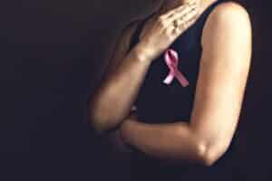 Woman wearing black tank top and pink breast cancer ribbon