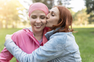 Woman wearing a headscarf receiving emotional support from a loved one during breast cancer treatment and recovery.