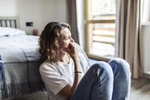 Woman sitting quietly at home while coping with anxiety and fear of breast cancer recurrence after treatment.