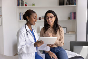 Woman working remotely at home Healthcare provider reviewing breast reconstruction information on a tablet with a patient during a consultation.