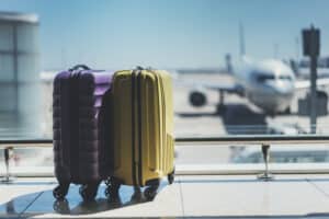 Two suitcases sitting by a window in an airport